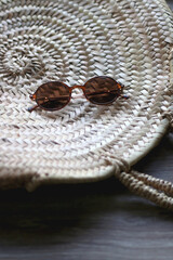 Wall Mural - Wicker tote bag and round sunglasses on a table. Selective focus.