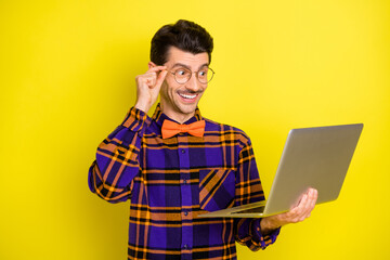 Canvas Print - Photo of young cheerful man happy positive smile look laptop watch seminar isolated over yellow color background