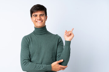 Handsome man over isolated blue background happy and pointing up