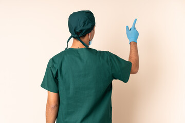 Wall Mural - Surgeon man in blue uniform over isolated background pointing back with the index finger