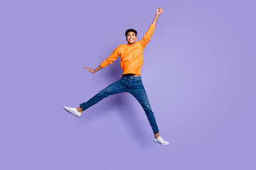 Sticker - Photo of funny sweet dark skin guy dressed orange pullover jumping rising arm hand isolated purple color background