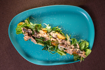 salad with tuna and herbs on a turquoise plate view from top