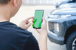 © photobuay - A Man standing next to the car. man using smartphone mockup green screen near the car. Mobile phone apps for car lock owners concept.
