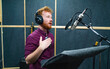 © Nik Viatkin - Expressive face of bearded man with red curly hair wear headphones near microphone who makes professional dubbing on a voice recording studio