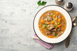 Beef and barley soup with celery, carrot and onion in plate on concrete background