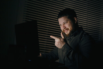 Smiling man talking by video call using laptop and showing forefinger.