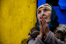 Grandmother Prays On A Yellow Background Close-up. An Elderly Woman In Prayer. An Old Grandmother In A Slum. Poor Grandmother Portrait Photo. Poverty. Seniors Concept.Old Grandmother's Prayer