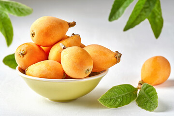 Wall Mural - Loquat fruit. Nispero. Eriobotrya Japonica. Loquat in bowl with fresh leaves. Close up