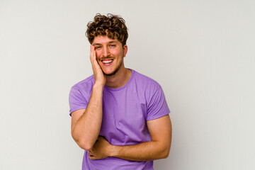 Wall Mural - Young caucasian man isolated on white background laughs happily and has fun keeping hands on stomach.