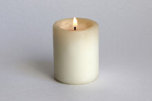 The Candle Burns Brightly On A White Background.