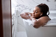 © Roman - Luxury bath african woman relaxing in hotel spa bathtub or home bathroom for total relaxation