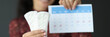Woman holding sanitary pads and calendar with red numbers closeup
