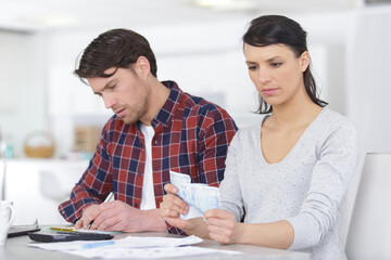 Wall Mural - couple embracing and calculating the bills at home