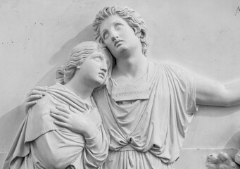 Black and white photo of marble sculpture representing a sad couple holding each other 