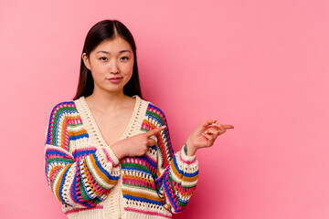 Wall Mural - Young chinese woman isolated on pink background shocked pointing with index fingers to a copy space.