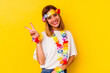 © Asier - Young caucasian woman celebrating a hawaiian party isolated on yellow background joyful and carefree showing a peace symbol with fingers.