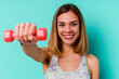 © Asier - Young sport skinny caucasian holding a dumbbell woman isolated on blue background