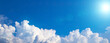 Blue sky background with white puffy clouds on a bottom foreground. Wide shot with cumulus clouds and cold blue sun. Banner, copy space, blank space for text