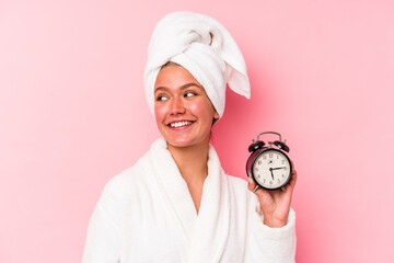 Poster - Young venezuelan woman late for work isolated on pink background looks aside smiling, cheerful and pleasant.