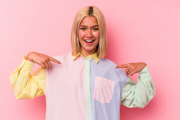 Poster - Young venezuelan woman isolated on pink background surprised pointing with finger, smiling broadly.