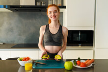 Athletic Woman With Gym Clothes Eats Fruits In The Kitchen