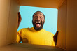 Happy man receives a package from online shop order. happy and surprised expression. cyan background.