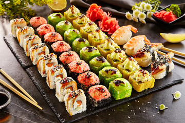 Canvas Print - Sushi bar set - International maki sushi roll on black slate platter. Served with wooden chopstick, wasabi and pickled ginger. Japanese set with maki sushi roll and nigiri sushi on dark stone table..