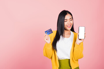 Wall Mural - Happy Asian portrait beautiful cute young woman excited smiling hold mobile phone and plastic debit credit bank card, studio shot isolated on pink background, female using smartphone online shopping