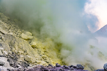 Ijen volcano crater and sulphur mining. Beautiful Landscape mountain and green lake with smoke sulfur in the morning in a Kawah Ijen volcano. Beautiful landmark from East Java, Indonesia