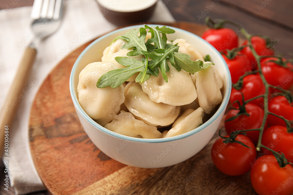 Bowl with tasty dumplings on wooden background
