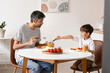 © Pixel-Shot - Father and his little son having breakfast in kitchen
