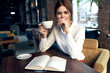 © SHOTPRIME STUDIO - woman in a restaurant with a notepad on the table and a cup in hand