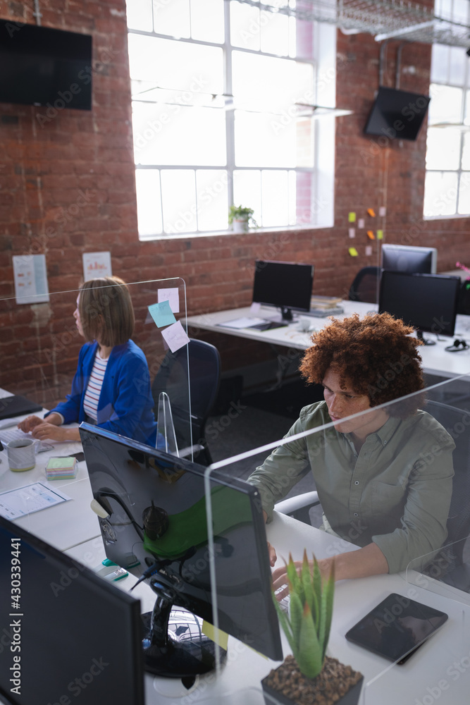 Diverse male and female colleagues sitting in front of computers ...