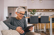 © bnenin - Beautiful older woman using tablet at home.