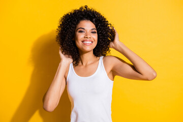Wall Mural - Photo of adorable satisfied dark skin person hands touch wavy hairdo toothy smile isolated on yellow color background