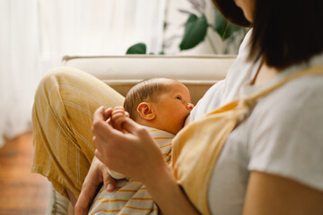 Newborn baby boy sucking milk from mothers breast. Portrait of mom and breastfeeding baby.