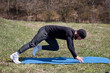© Igor Syrbu - Playful sportsman extends leg behind him on fitness mat in the park