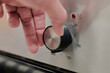 A man's hand turning the temperature control wheel of an oven to 180 degrees celsius