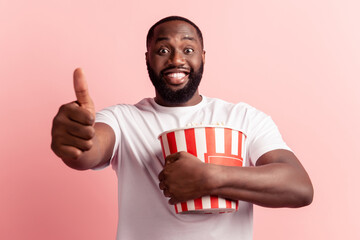 Wall Mural - Man with popcorns bucket raise thumb-up toothy smile