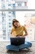 © dianagrytsku - Cheerful young woman having a videocall while sitting on a floor with laptop computer