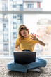 © dianagrytsku - Cheerful young woman having a videocall while sitting on a floor with laptop computer