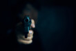 © Konstantin Savusia - Muzzle of gun in man's hand is pointed at camera. Threat of firearms. Male criminal holds revolver on black background. Attack or defense.
