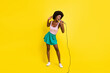 Full size photo of pretty afro american charming woman wear pink singlet good singer karaoke isolated on yellow color background