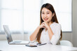 © Chanakon - Young asian beautiful business woman working with laptop sitting at home. Smiling charming happy young female doing homework meeting conference with team at home.