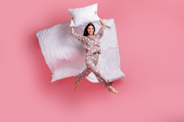 Poster - Full length photo of adorable young woman sleepwear jumping high holding pillow duvet isolated pink color background