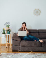 Wall Mural - Smiling business woman sitting on sofa, talking on phone and working from home on laptop computer
Happy businesswoman teleconferencing with business partner or client, telecommuting concept