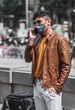 © Tato_Torrejon - Good looking young adult man wearing casual spring clothes outdoor,  talking and texting on phone in padendemic day taking measure with face mask.