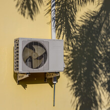 Air Conditioner Compressor Near Palm Leaf Shadow.