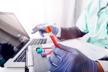 Laboratory pipette with drop of liquid over glass test tubes for an experiment in a science research lab .Man wears protective goggles