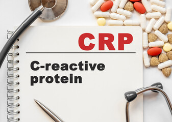 Page in notebook with CRP on white background with stethoscope and group of pill. Medical concept. Term and abbreviation. C reactive protein